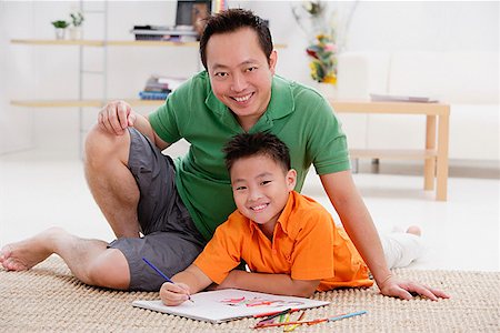 simsearch:656-01773033,k - Vater und Sohn im Wohnzimmer, lächelnd in die Kamera, Materialien, um sie herum zeichnen Stockbilder - Premium RF Lizenzfrei, Bildnummer: 656-01773024