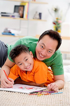 simsearch:656-01768177,k - Father and son at home, lying on floor with sketch pad, smiling at camera Stock Photo - Premium Royalty-Free, Code: 656-01773027