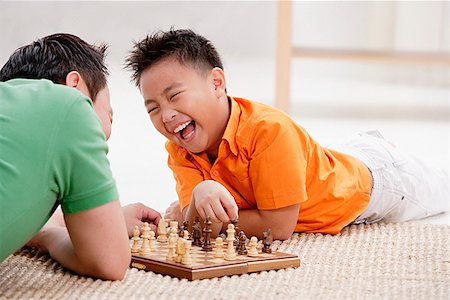 simsearch:656-01768260,k - Father and son lying on floor, playing chess, laughing Fotografie stock - Premium Royalty-Free, Codice: 656-01773033