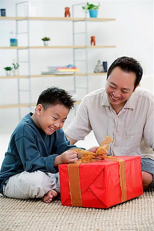 Boy opening gift box, father next to him Stock Photo - Premium Royalty-Free, Code: 656-01773044