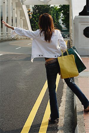 Woman standing by road, waving for taxi, rear view Foto de stock - Sin royalties Premium, Código: 656-01773307