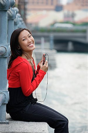simsearch:656-01773308,k - Femme assise au bord de rivière, à l'écoute de MP3 player, portrait Photographie de stock - Premium Libres de Droits, Code: 656-01773369