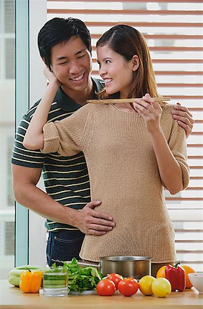 photo of a woman feeding her husband food - Man embracing woman from behind, woman feeding man Stock Photo - Premium Royalty-Free, Code: 656-01773435