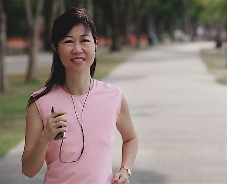 Mature woman walking in park, listening to MP3 player Stock Photo - Premium Royalty-Free, Code: 656-01773607