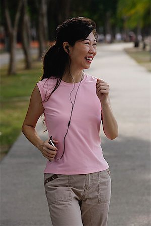 Mature femme marchant dans le parc, à l'écoute pour lecteur MP3, souriant Photographie de stock - Premium Libres de Droits, Code: 656-01773608