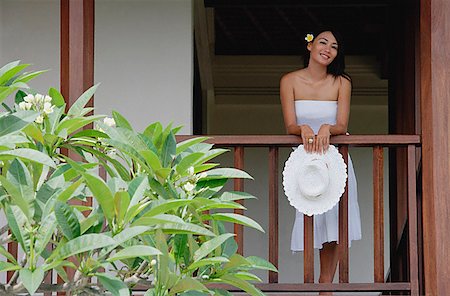 simsearch:656-01773782,k - Jeune femme debout au balcon, tenant le chapeau, sourire Photographie de stock - Premium Libres de Droits, Code: 656-01773777