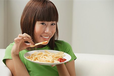 french fry smile - Young woman eating a plate of French fries Stock Photo - Premium Royalty-Free, Code: 656-01773886