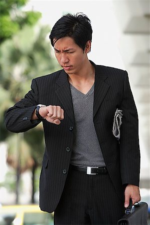simsearch:656-01773928,k - Businessman holding briefcase, looking at watch, frowning Foto de stock - Royalty Free Premium, Número: 656-01773903