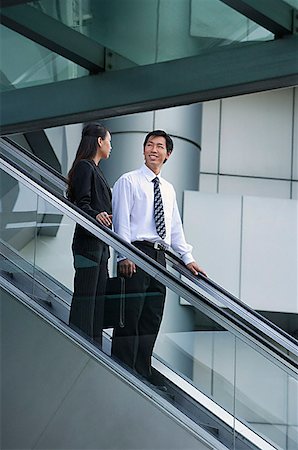 Businessman and businesswoman on escalator Stock Photo - Premium Royalty-Free, Code: 656-01773918