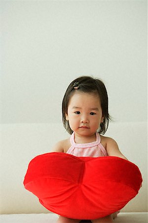 Baby girl with heart-shaped cushion Stock Photo - Premium Royalty-Free, Code: 656-01828924