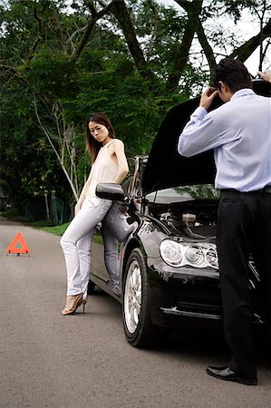 Man looking under hood of car while woman waits Stock Photo - Premium Royalty-Free, Code: 656-02371876