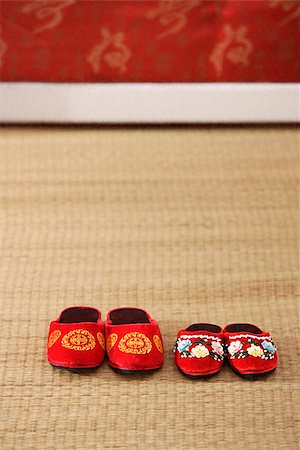 Still life of 2 pairs of red shoes on weaved mat Stock Photo - Premium Royalty-Free, Code: 656-02660226