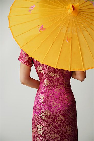 young Chinese woman in pink cheongsam holding yellow umbrella Stock Photo - Premium Royalty-Free, Image code: 656-02702831