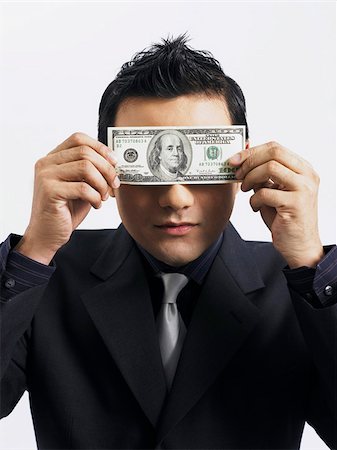 man holding up an American bill against his eyes Stock Photo - Premium Royalty-Free, Code: 656-02879474