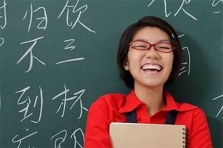 woman laughing in front of Chinese characters written on chalk board Foto de stock - Royalty Free Premium, Número: 656-02879691