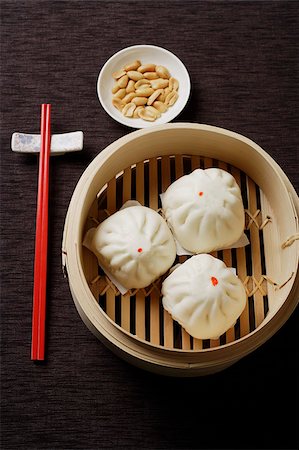 dim sum - Steamed buns in bamboo steamers with red chopsticks Stock Photo - Premium Royalty-Free, Code: 656-03076218