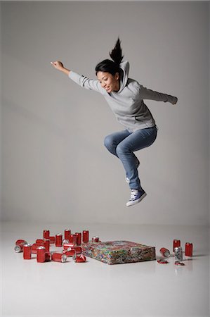 Young Asian woman jumping on cans Stock Photo - Premium Royalty-Free, Code: 656-03240974