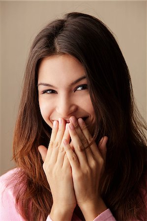 eurasian - young woman laughing while covering her mouth with her hands Stock Photo - Premium Royalty-Free, Code: 656-03519514