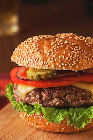 Cheeseburger juteux avec tomates, oignons et cornichons sur pain de graines de sésame Photographie de stock - Premium Libres de Droits, Code: 659-06154225