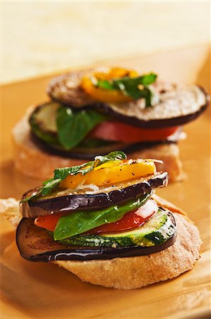 Slices of Bread Topped with Sliced Eggplant, Zucchini, Tomato and Yellow Pepper and Drizzled with Olive Oil Stock Photo - Premium Royalty-Free, Code: 659-06154230