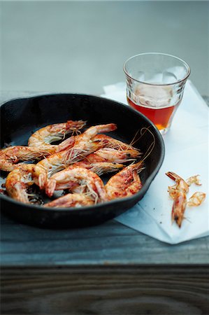 shrimp in frying pan dish - Pan Fried Shrimp in Skillet; Peels and a Glass of Beer Stock Photo - Premium Royalty-Free, Code: 659-06154257