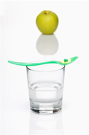 simsearch:659-06185696,k - Eine Vitamin-Tablette auf einem Löffel auf ein Glas Wasser mit einem grünem Apfel im Hintergrund Stockbilder - Premium RF Lizenzfrei, Bildnummer: 659-06151401
