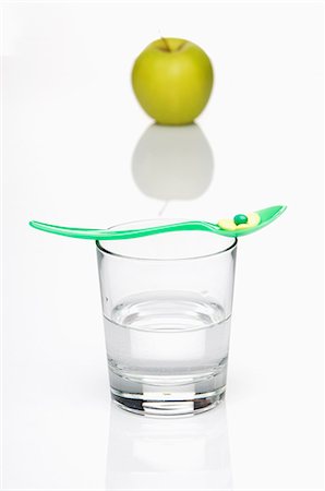 simsearch:659-06183745,k - A vitamin tablet on a spoon on top of a glass of water with a green apple in the background Foto de stock - Sin royalties Premium, Código: 659-06151401