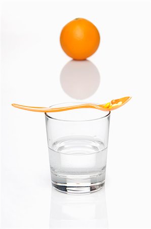 Vitamin tablets on a spoon on top of a glass of water with an orange in the background Stock Photo - Premium Royalty-Free, Code: 659-06151402