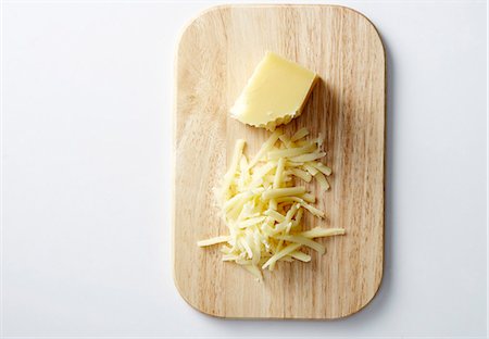 queso rallado - Gruyere, partially grated, on a chopping board Foto de stock - Sin royalties Premium, Código: 659-06151687
