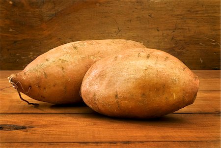 sweet potatoes raw - Two Sweet Potatoes on Wooden Table Stock Photo - Premium Royalty-Free, Code: 659-06151813