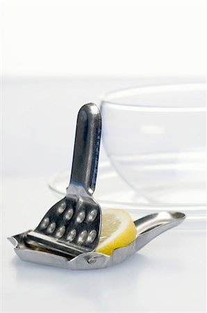 presse-agrumes - Une presse citron avec une tranche de citron et un verre de thé à l'arrière-plan Photographie de stock - Premium Libres de Droits, Code: 659-06151949