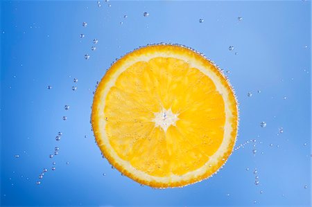 A slice of orange in blue water with air bubbles Stock Photo - Premium Royalty-Free, Code: 659-06152044