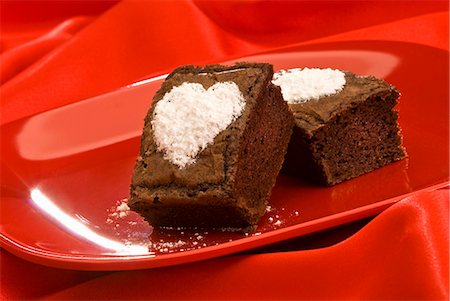 Deux ""brownie"" avec des cœurs de sucre en poudre sur une plaque rouge Photographie de stock - Premium Libres de Droits, Code: 659-06152164
