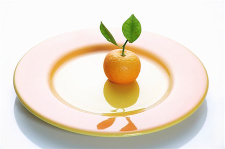 A clementine with leaves on a plate Stock Photo - Premium Royalty-Free, Code: 659-06152255