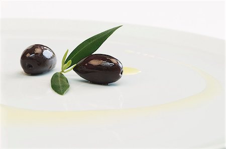 schwarze olive - Kalamata Oliven mit Blättern und Olivenöl auf einem Teller Stockbilder - Premium RF Lizenzfrei, Bildnummer: 659-06152314