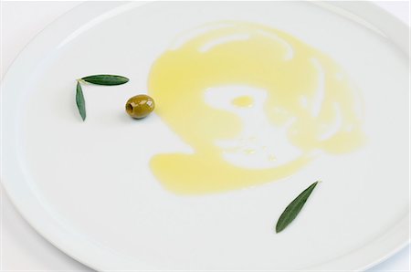 Olive oil, green olives and olive leaves on a plate Stock Photo - Premium Royalty-Free, Code: 659-06152312