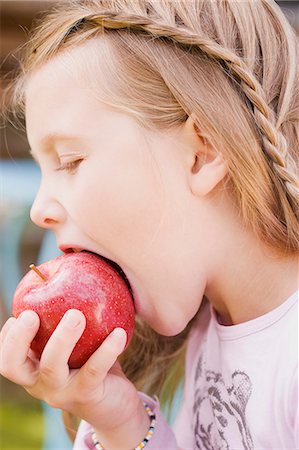 Une jeune fille de mordre dans une pomme Photographie de stock - Premium Libres de Droits, Code: 659-06153021