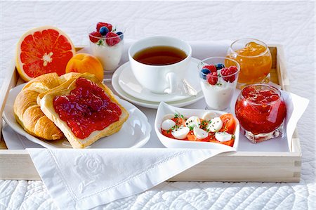 Breakfast in bed with tea, jam, yogurt, fruit and tomatoes and mozzarella Fotografie stock - Premium Royalty-Free, Codice: 659-06153051