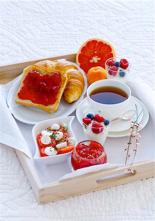 Breakfast in bed with tea, jam, yogurt, fruit and tomatoes and mozzarella Fotografie stock - Premium Royalty-Free, Codice: 659-06153052