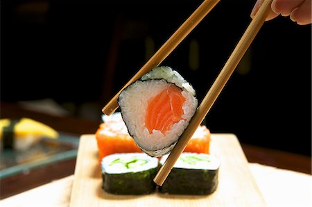 seafood food presentation - A hand holding a maki sushi in chopsticks Stock Photo - Premium Royalty-Free, Code: 659-06153100