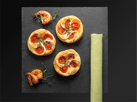 Pâte feuilletée tartelettes à la pâte à tarte avec le fromage de chèvre et tomates sur une plaque d'ardoise Photographie de stock - Premium Libres de Droits, Code: 659-06153283