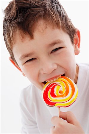 A little boy biting into a lolly Stock Photo - Premium Royalty-Free, Code: 659-06153341