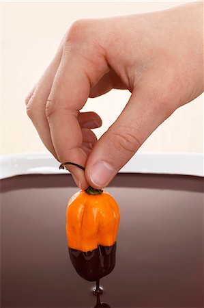 dipping sauces - Hand dipped yellow chili in chocolate sauce Stock Photo - Premium Royalty-Free, Code: 659-06153352