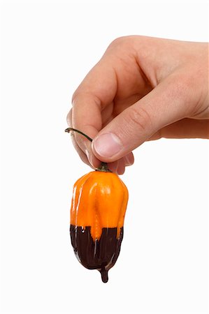 Hand holding a chili pepper dripping with melted chocolate Stock Photo - Premium Royalty-Free, Code: 659-06153353