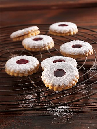 festive cookies - 'Spitzbuben' (jelly filled cookies) with powdered sugar on a cooling rack Stock Photo - Premium Royalty-Free, Code: 659-06153714