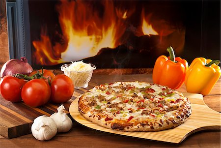 fuego - A chicken and vegetable pizza on a pizza paddle in front of a wood-fired oven Foto de stock - Sin royalties Premium, Código: 659-06153875