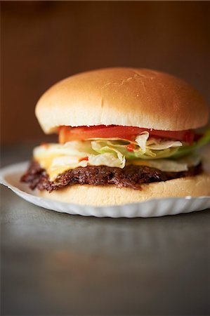 Cheeseburger grillé avec laitue et tomate sur une assiette en carton Photographie de stock - Premium Libres de Droits, Code: 659-06153914