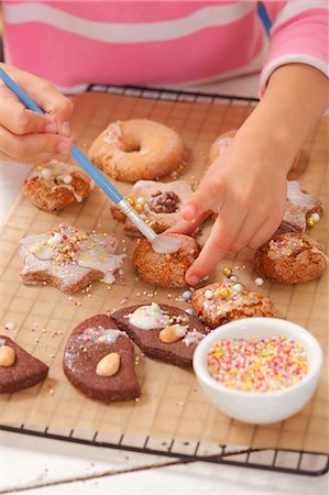 dolci natalizi - A girl decorating biscuits with icing sugar Fotografie stock - Premium Royalty-Free, Codice: 659-06184213