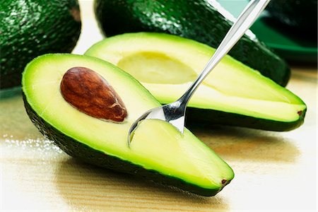 An avocado, halved, with a spoon Stock Photo - Premium Royalty-Free, Code: 659-06184229