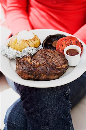patata al horno - Woman holding plate of steak, baked potato, vegetables & sauce Foto de stock - Sin royalties Premium, Código: 659-06184435